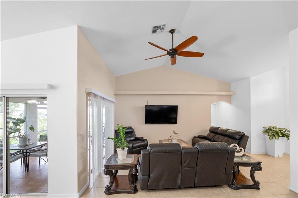 Living room with ceiling fan, light tile patterned floors, and arched walkways