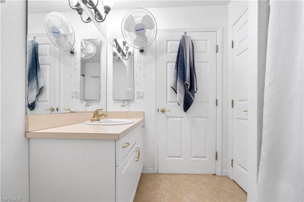Bathroom featuring vanity, curtained shower, and light tile patterned flooring