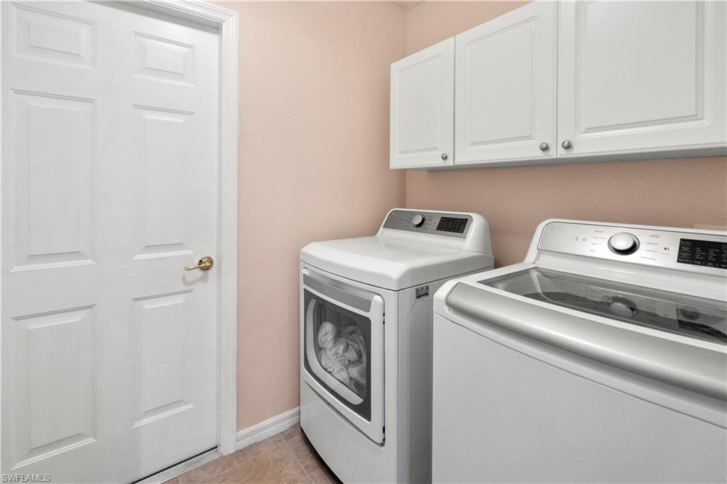 Laundry room featuring cabinet space, separate washer and dryer, and light tile patterned flooring