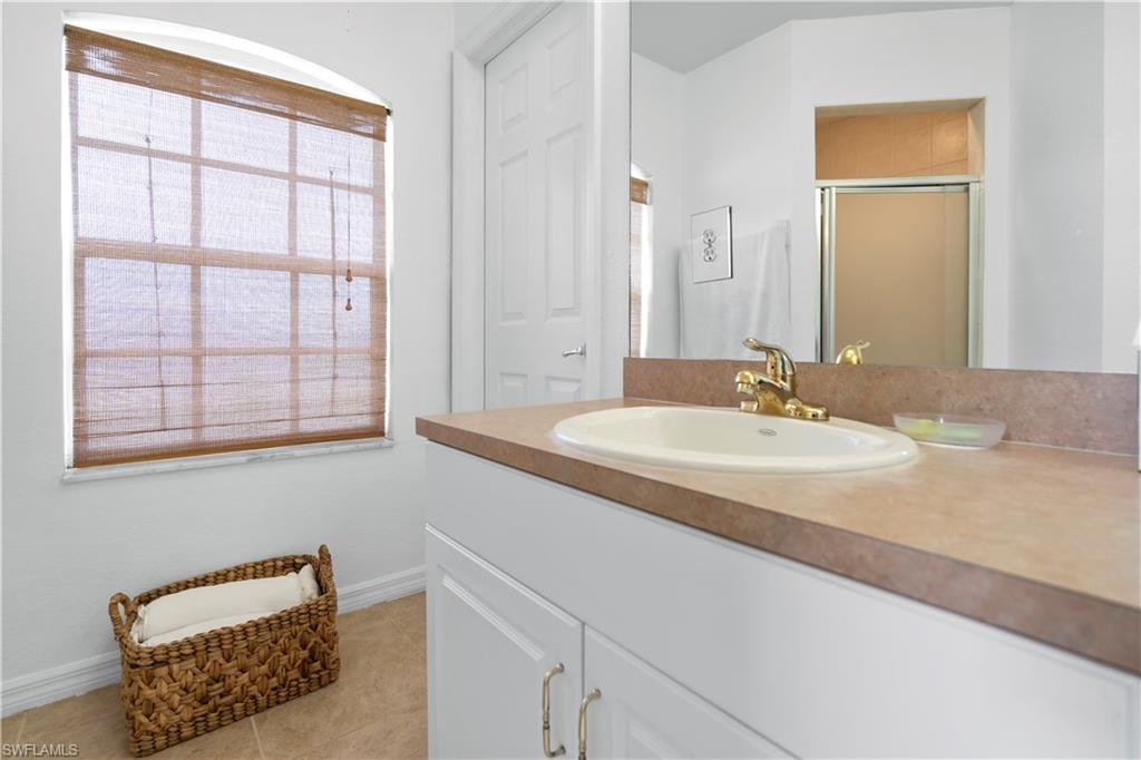 Full bath featuring vanity, a stall shower, and light tile patterned floors