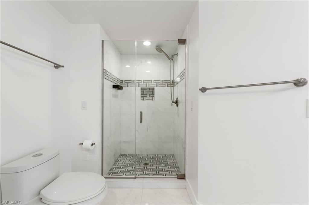 Glass-enclosed shower featuring a tiled floor in a herringbone pattern and wall tiles with a decorative accent band