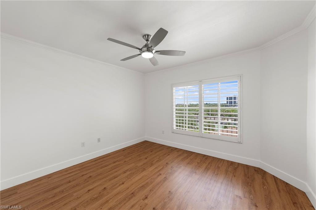 Room featuring wood-finish flooring, white walls, and crown molding
