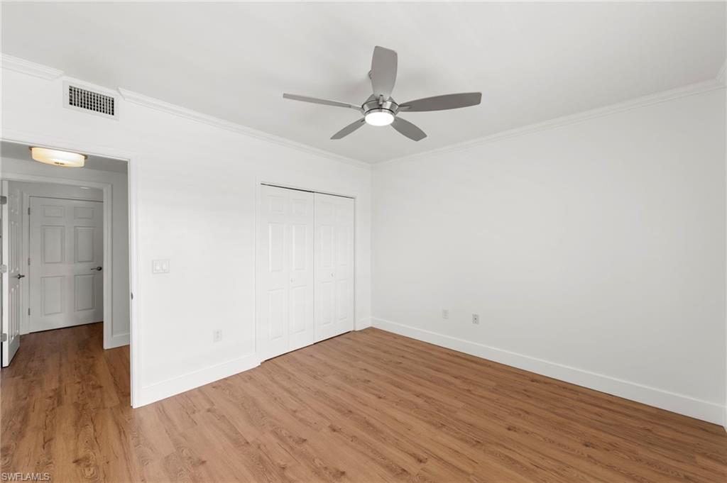 Spacious room featuring wood-finish flooring, white walls, and a modern ceiling fan with integrated lighting