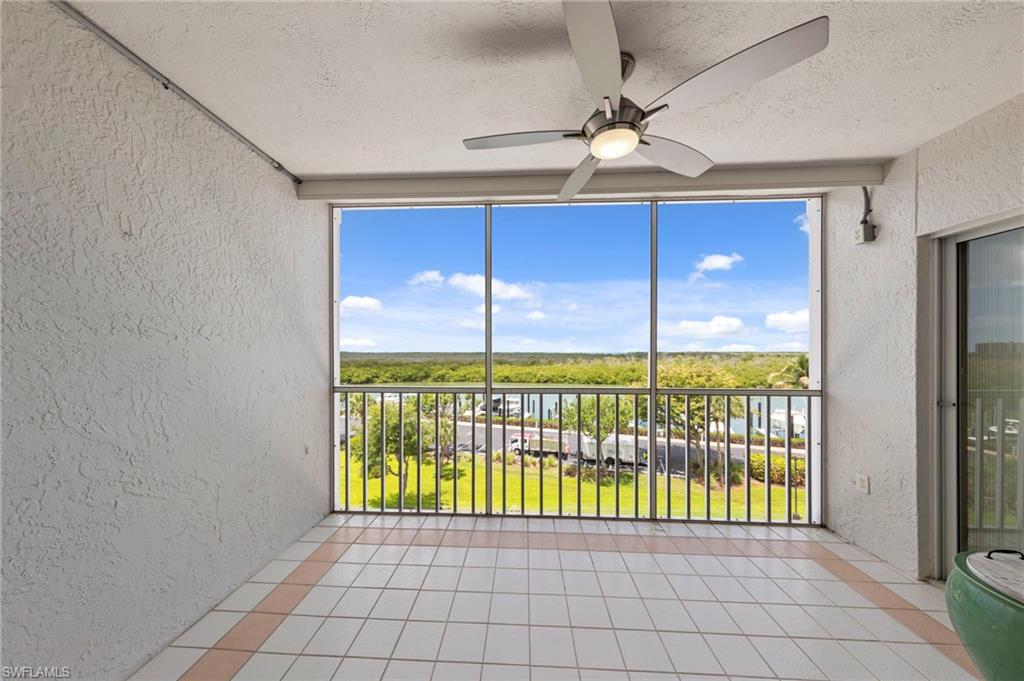 Expansive screened patio featuring a ceiling fan with integrated lighting, tile flooring, and a metal railing system