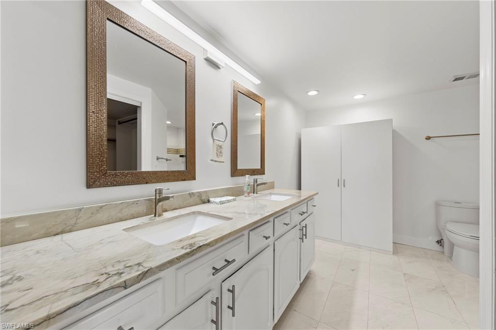 Dual vanity with white cabinetry, under-mount sinks, and a stone countertop