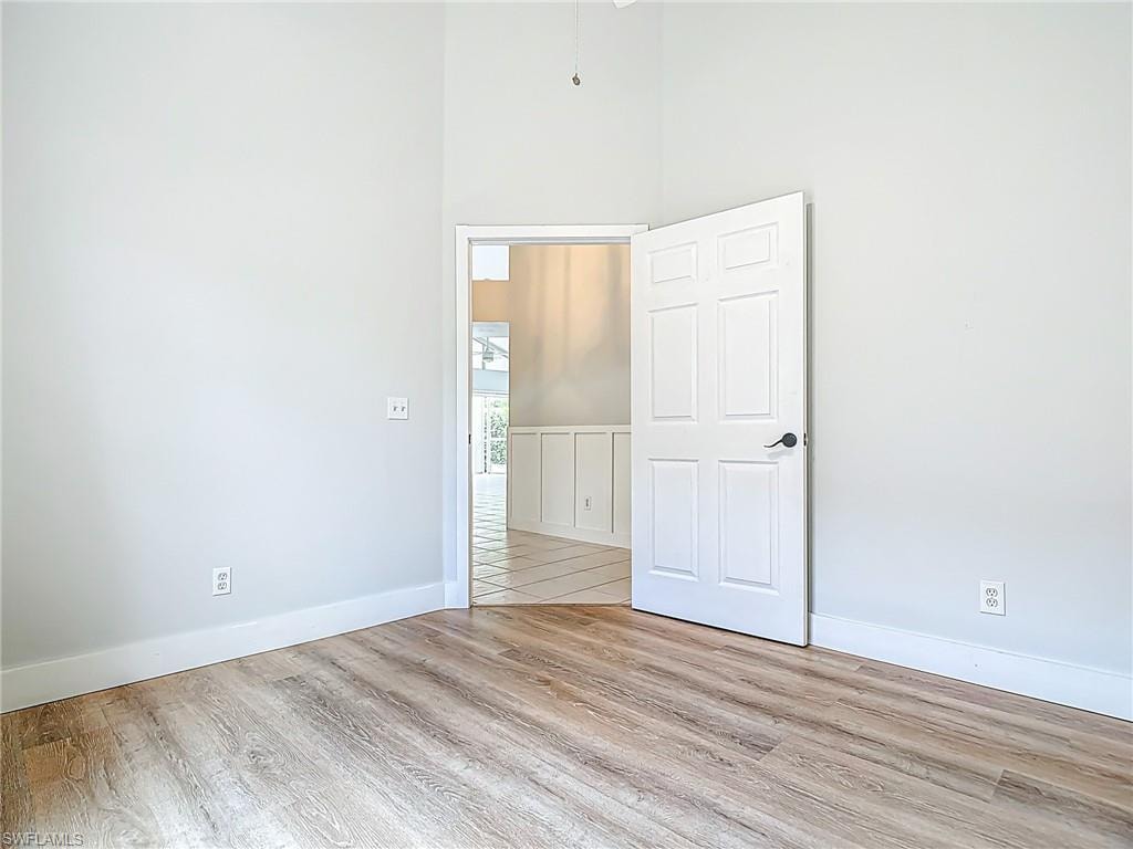 Spare room with baseboards, a high ceiling, and wood finished floors