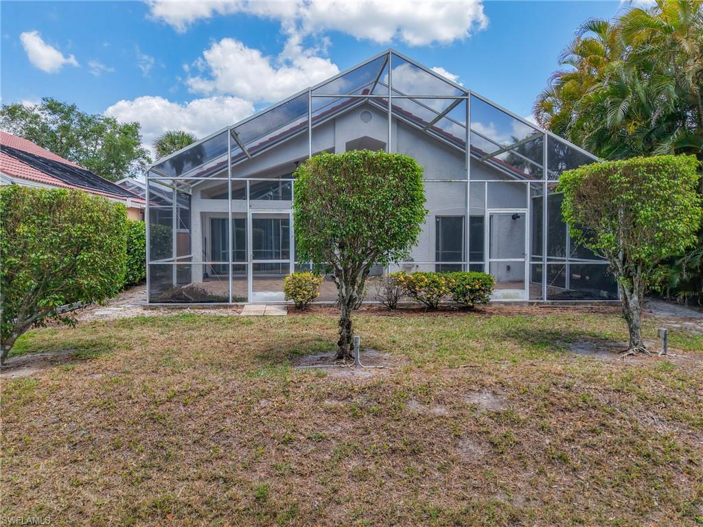 Back of property with a lawn and a lanai