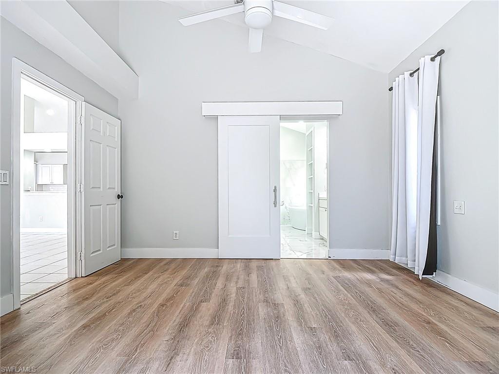 Spare room featuring a ceiling fan, baseboards, vaulted ceiling, and wood finished floors