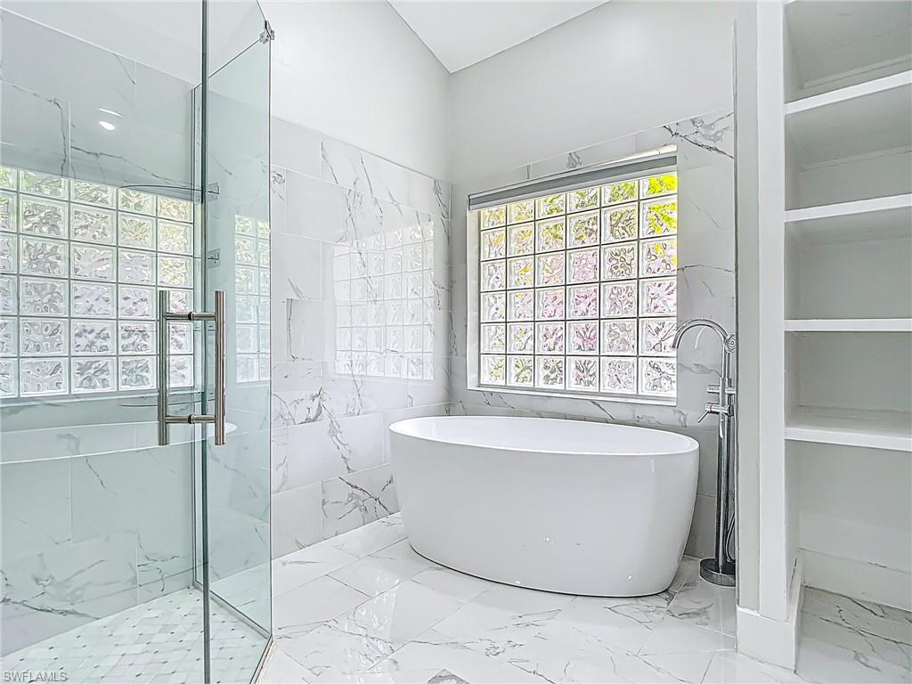 Full bathroom with a freestanding bath, a healthy amount of sunlight, a marble finish shower, and marble finish floor