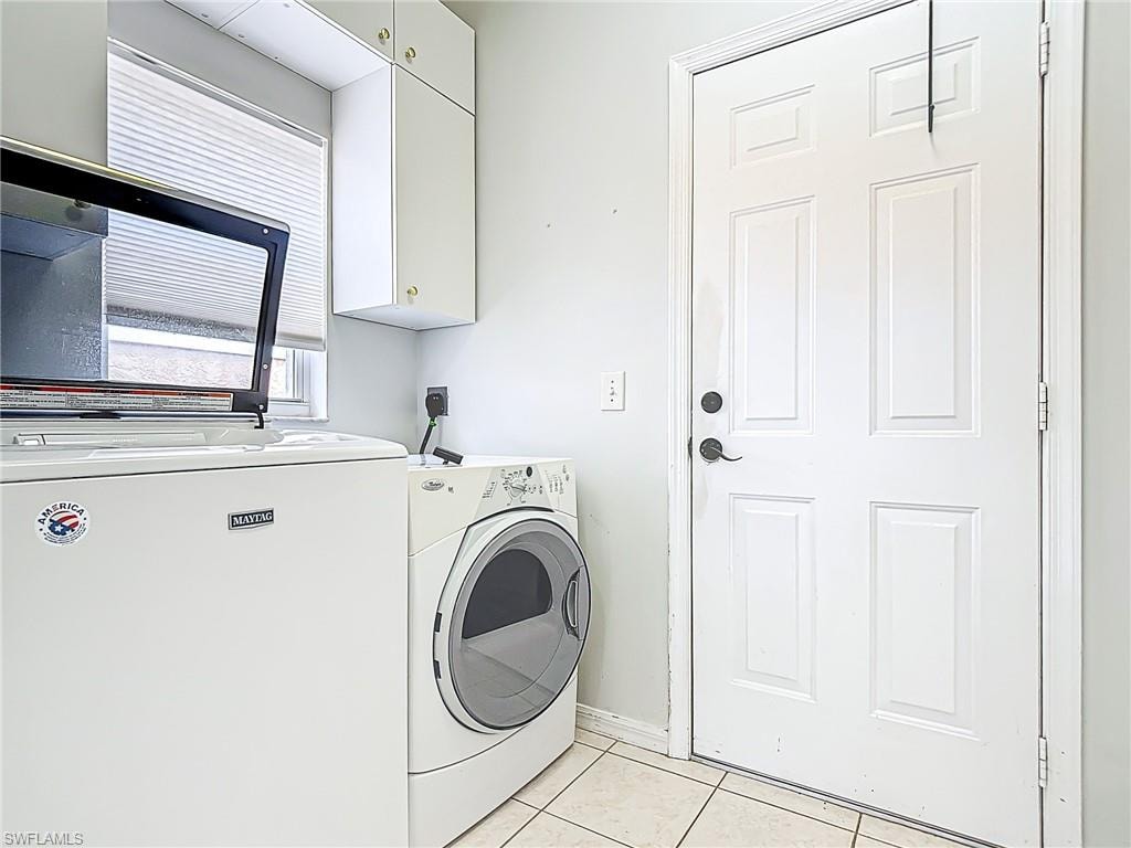 Laundry area featuring cabinet space, separate washer and dryer, baseboards, and light tile patterned floors