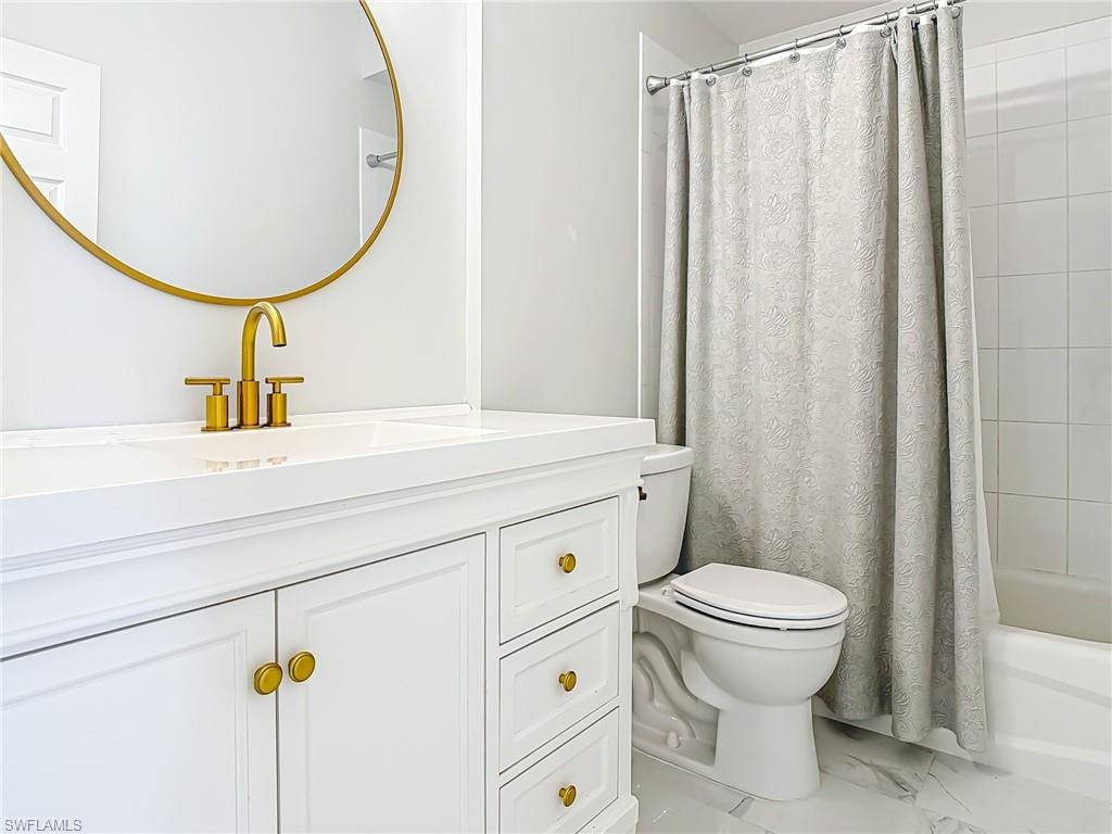 Full bathroom with toilet, shower / bathtub combination with curtain, marble finish floor, and vanity