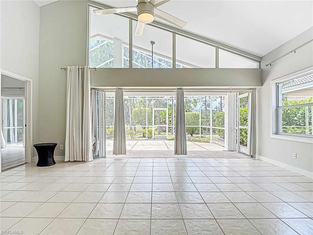 Unfurnished living room with light tile patterned floors, high vaulted ceiling, and a wealth of natural light