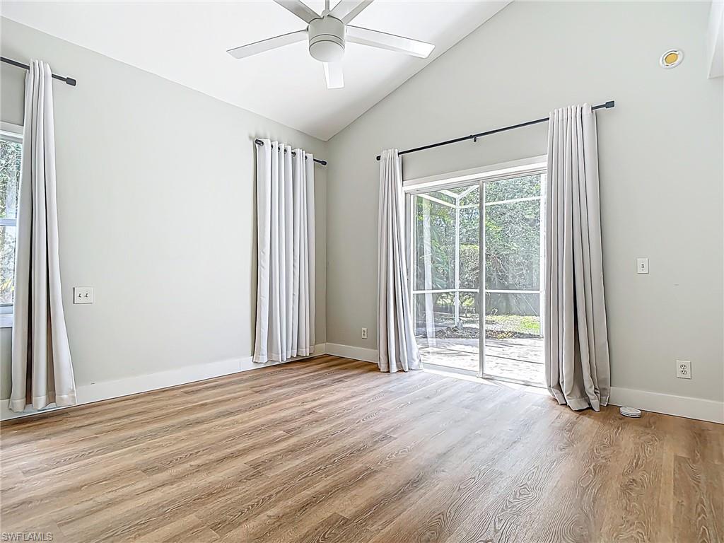 Spare room featuring plenty of natural light, a ceiling fan, light wood-type flooring, and lofted ceiling