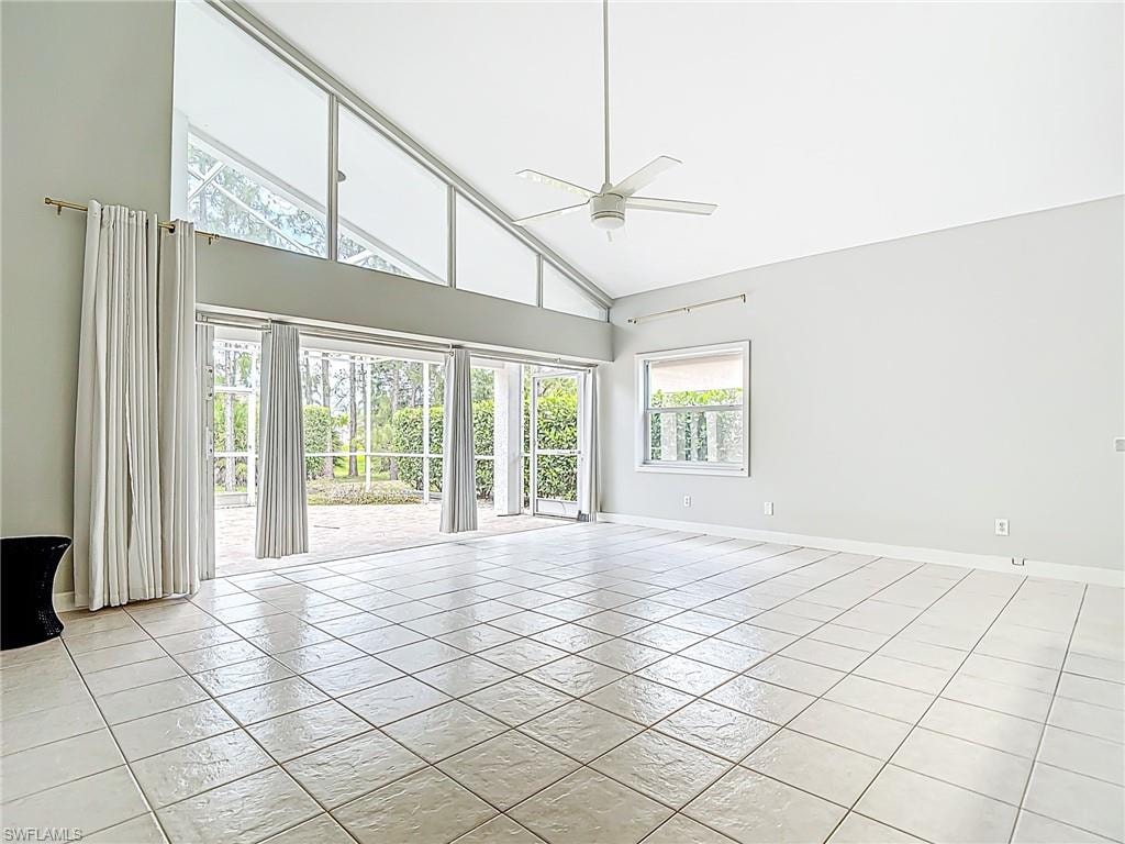 Unfurnished room featuring baseboards, ceiling fan, light tile patterned flooring, and high vaulted ceiling