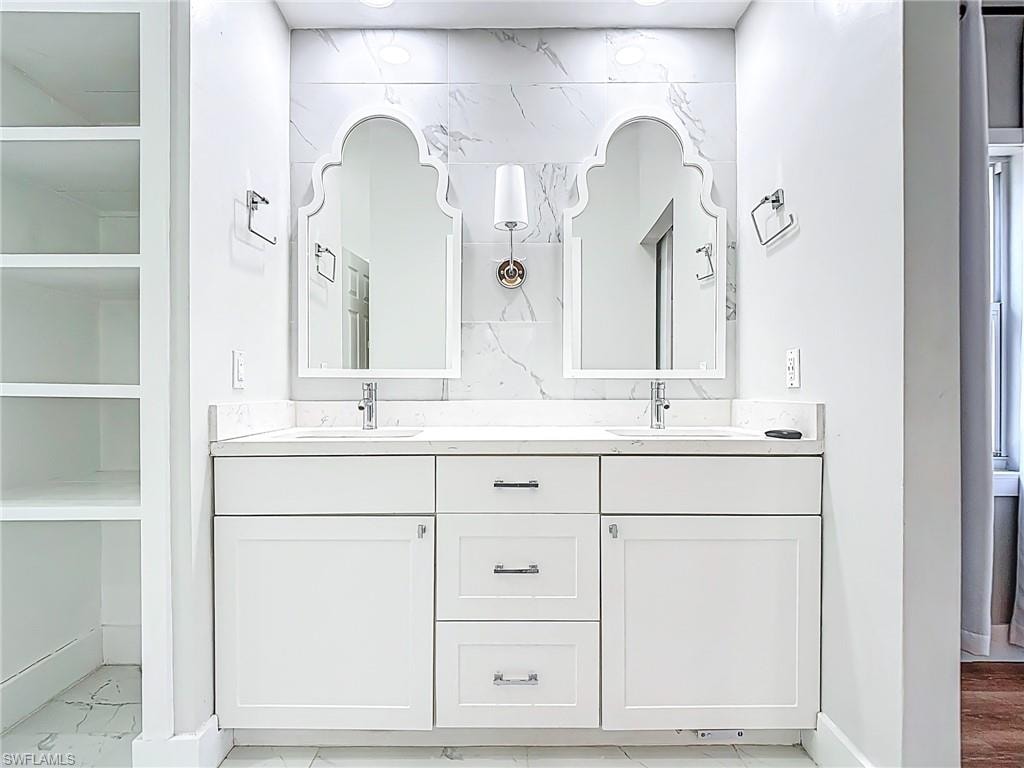Full bath with double vanity, a sink, and baseboards