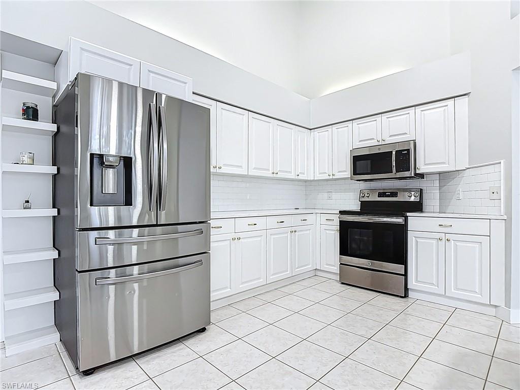Kitchen featuring light countertops, backsplash, appliances with stainless steel finishes, and light tile patterned floors