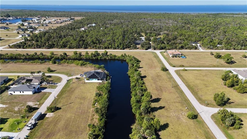 Aerial overview of property's location with a nearby body of water and a forest