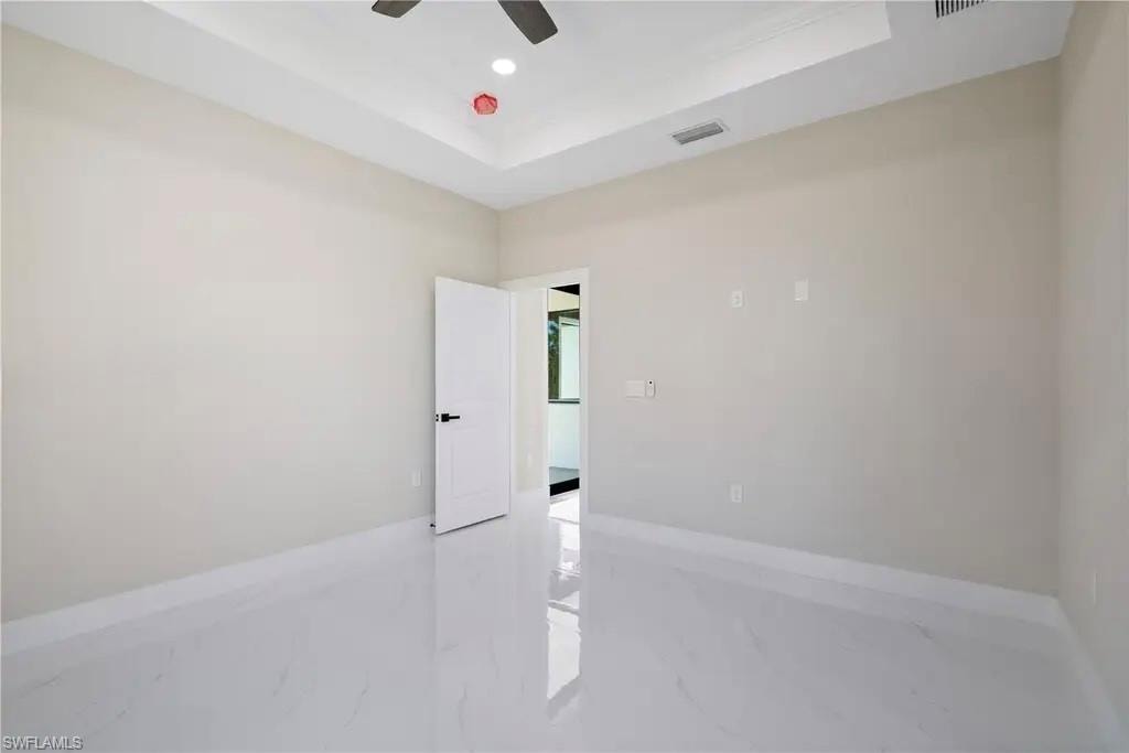 Spare room with a raised ceiling, ceiling fan, light marble finish flooring, and recessed lighting