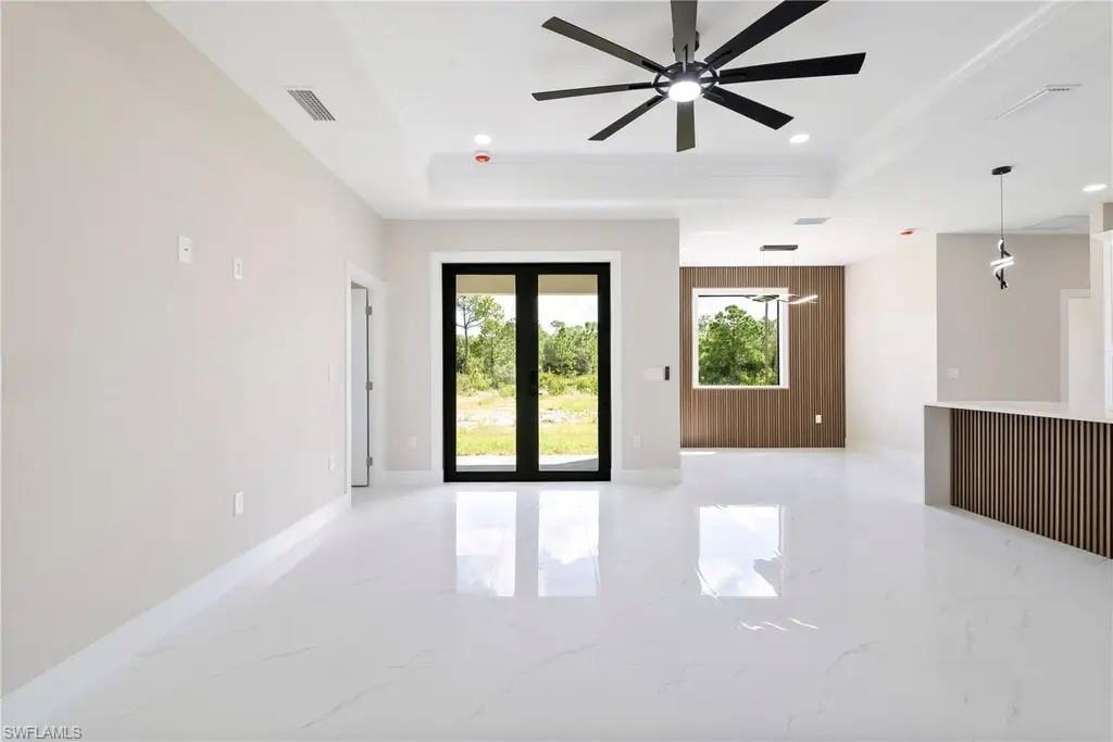 Unfurnished living room featuring a tray ceiling, french doors, light marble finish flooring, a ceiling fan, and recessed lighting