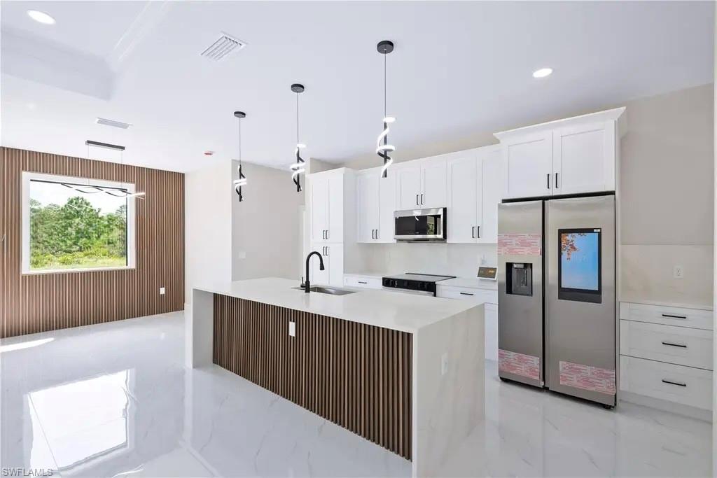 Kitchen featuring wood walls, stainless steel appliances, white cabinetry, light stone countertops, and light marble finish flooring