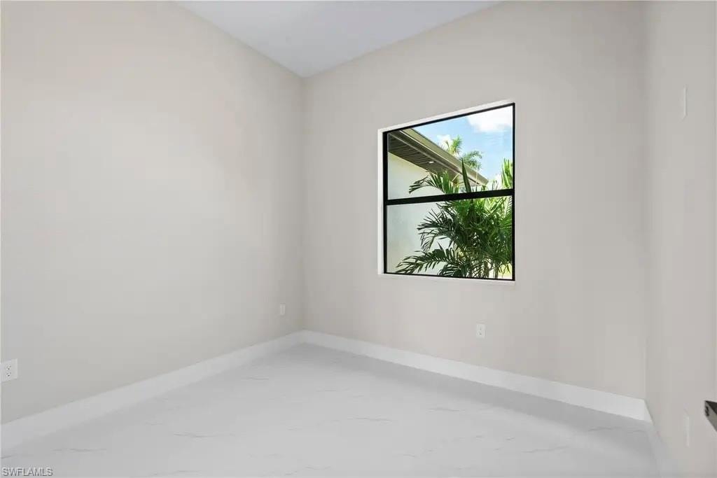 Unfurnished room featuring baseboards and light marble finish floors