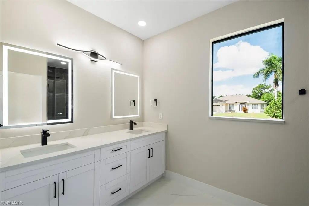 Bathroom with double vanity and light marble finish flooring