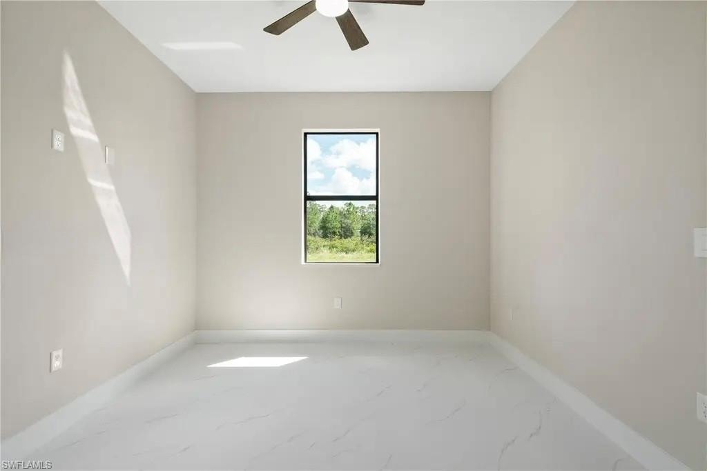 Unfurnished room featuring light marble finish flooring and ceiling fan