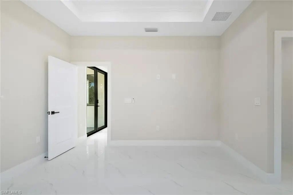 Spare room with a raised ceiling and light marble finish flooring