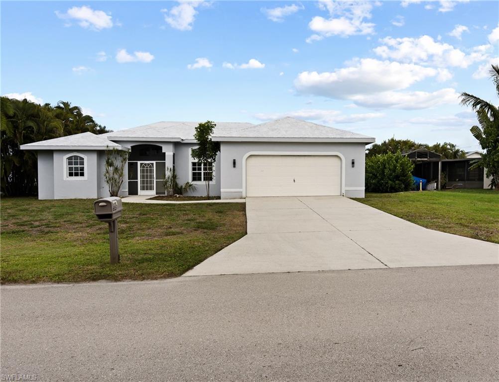 Single story home with a front yard, stucco siding, an attached garage, and concrete driveway