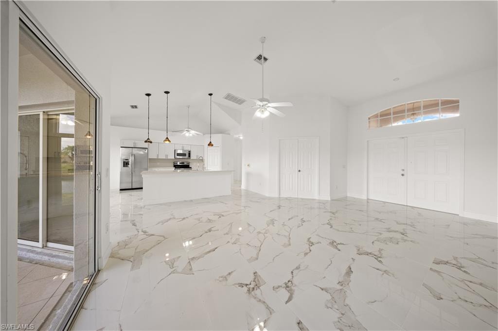 Unfurnished living room with a high ceiling, a ceiling fan, and light marble finish flooring