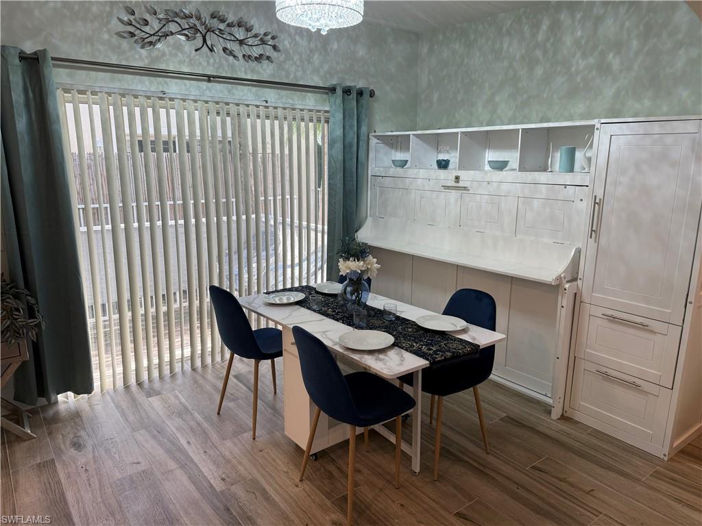 Wood-finish flooring, built-in wall unit with shelving, sliding glass door with vertical blinds, and a decorative wall fixture