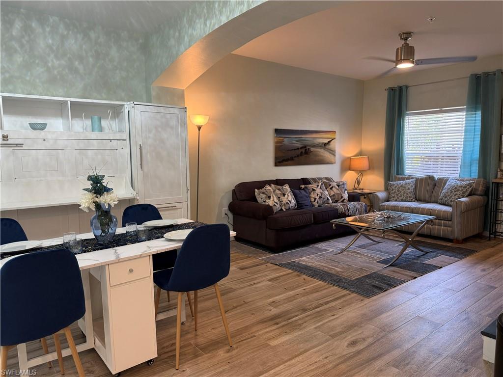 Wood-finish flooring throughout, featuring a built-in storage unit, contemporary ceiling fan, and window with blinds