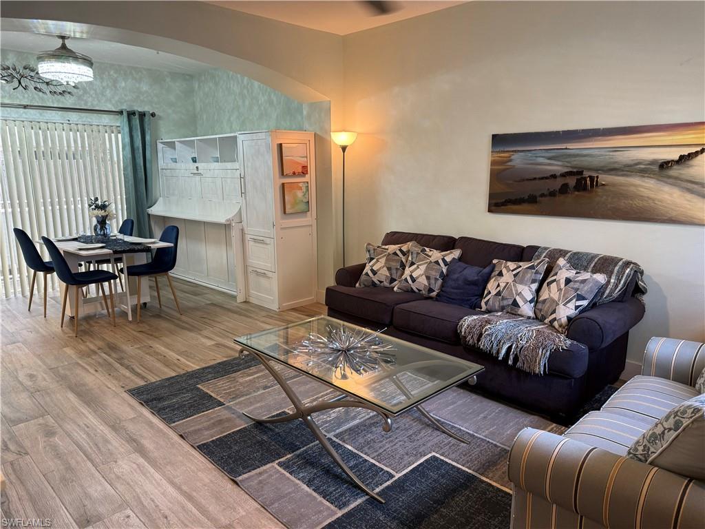 Open-concept living area with wood-finish flooring, an arched doorway, and built-in white cabinetry