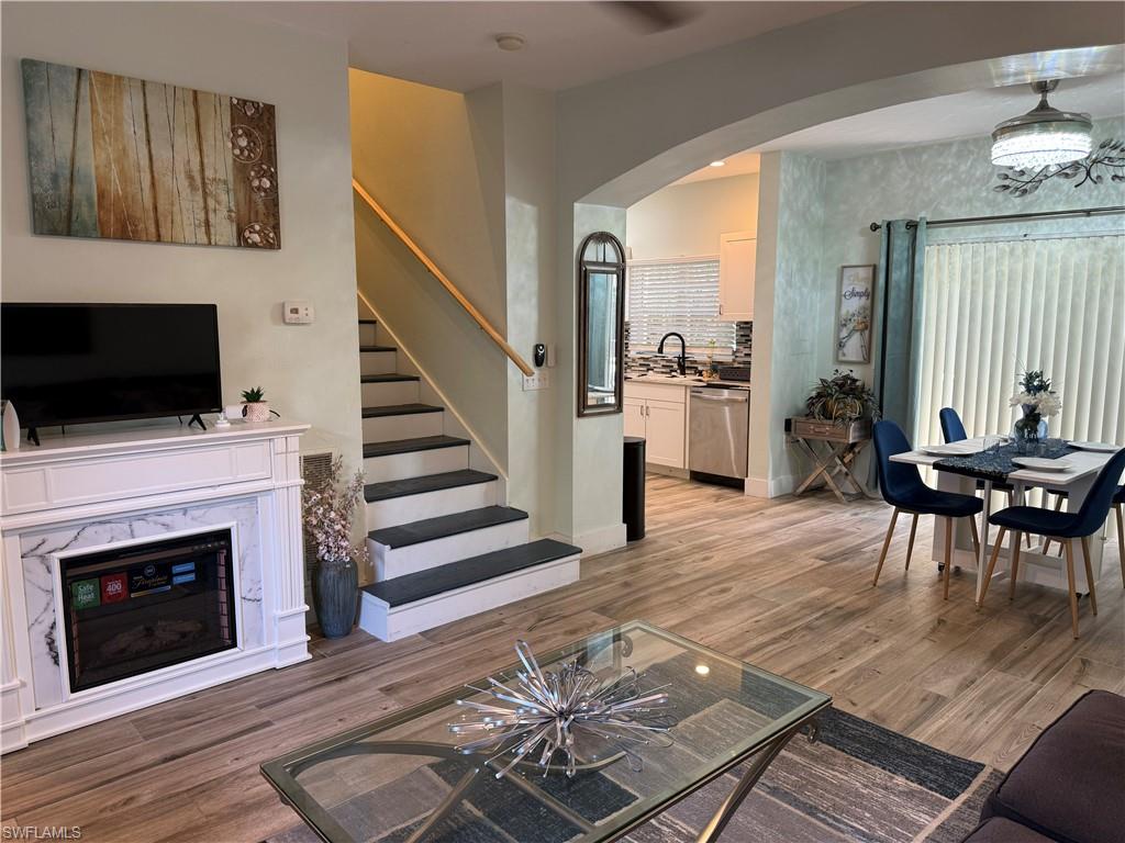 Wood-finish flooring throughout, a decorative fireplace with a marble-look surround, and a staircase with a wood handrail