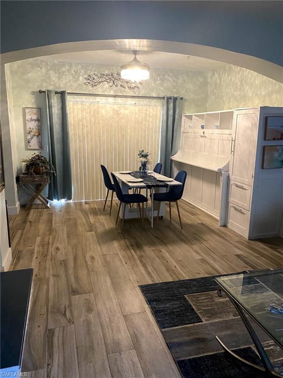 Wood-finish flooring, recessed lighting, arched entryway, and built-in white cabinetry