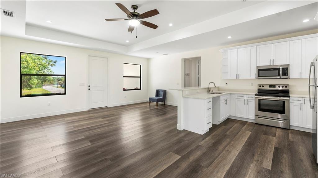Kitchen with stainless steel appliances, a peninsula, white cabinetry, a ceiling fan, and open floor plan