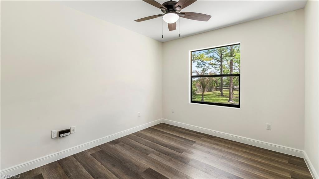 Spare room with dark wood-type flooring and a ceiling fan
