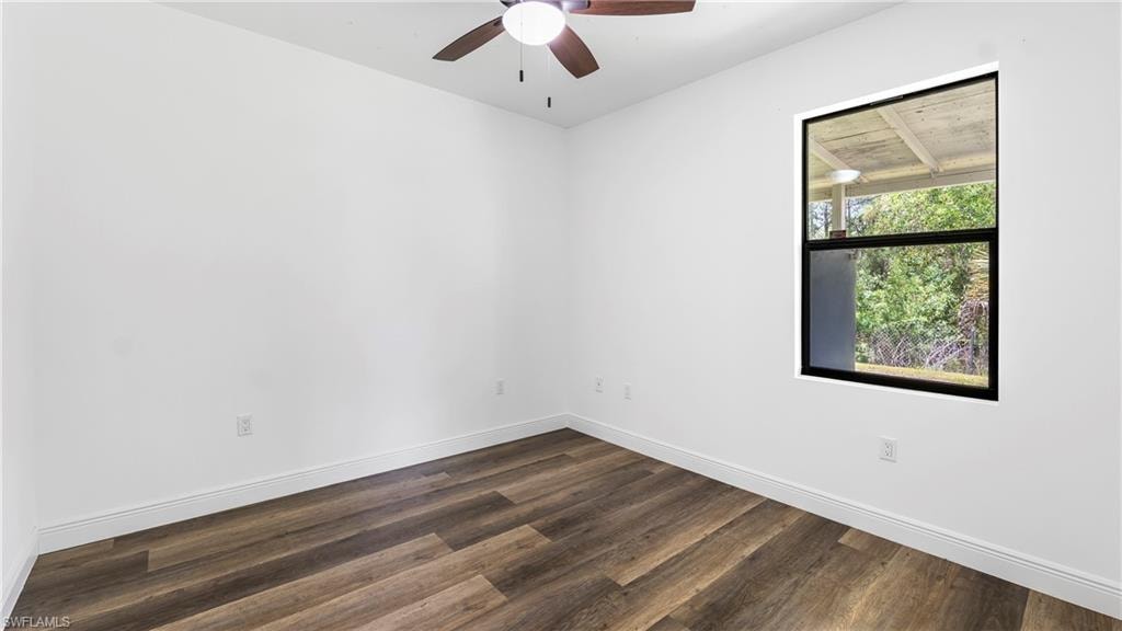 Empty room featuring dark wood-type flooring and ceiling fan
