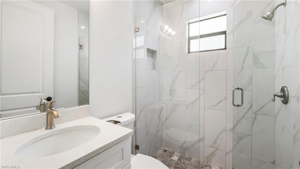 Bathroom featuring vanity and a marble finish shower