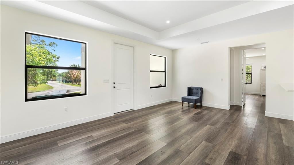 Unfurnished room with a tray ceiling, dark wood-style floors, and recessed lighting