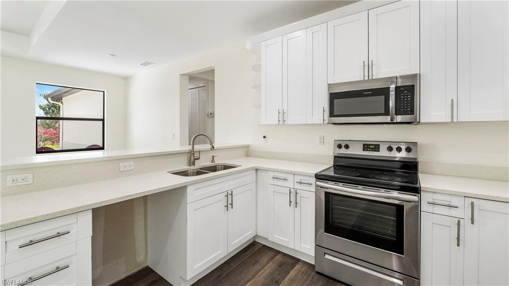 Kitchen featuring stainless steel appliances, white cabinets, dark wood-type flooring, open shelves, and light stone counters
