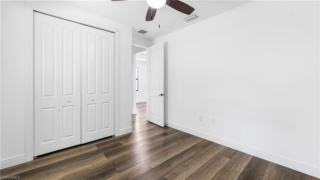 Unfurnished bedroom with dark wood-style floors, a closet, and ceiling fan