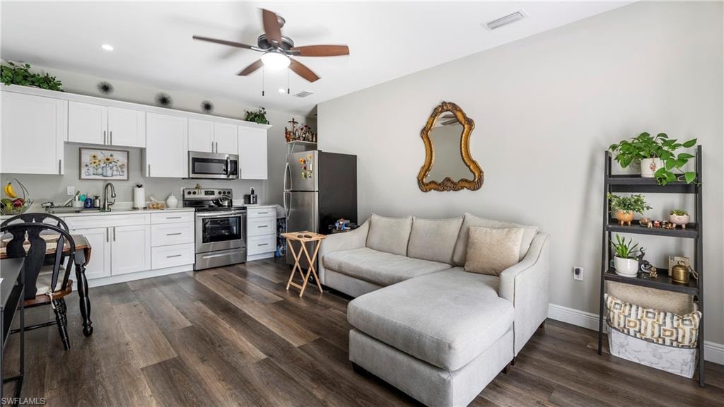 Living room with a ceiling fan and dark wood-type flooring