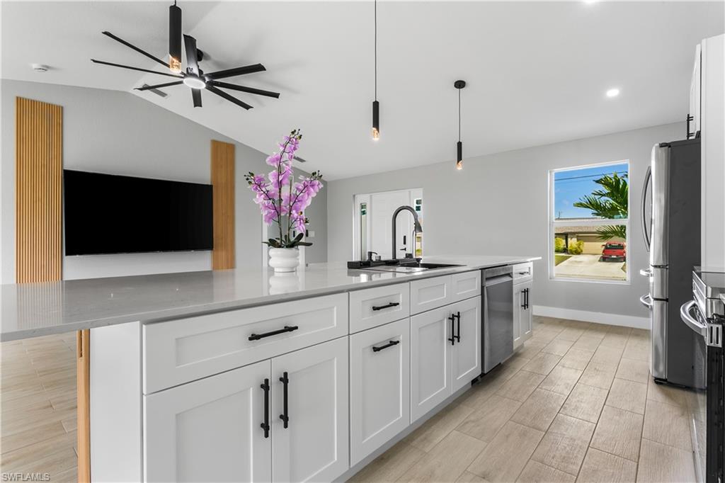 The chef-inspired kitchen is the heart of the home, showcasing an oversized quartz island & white shaker cabinetry paired with warm wood-tone accents.