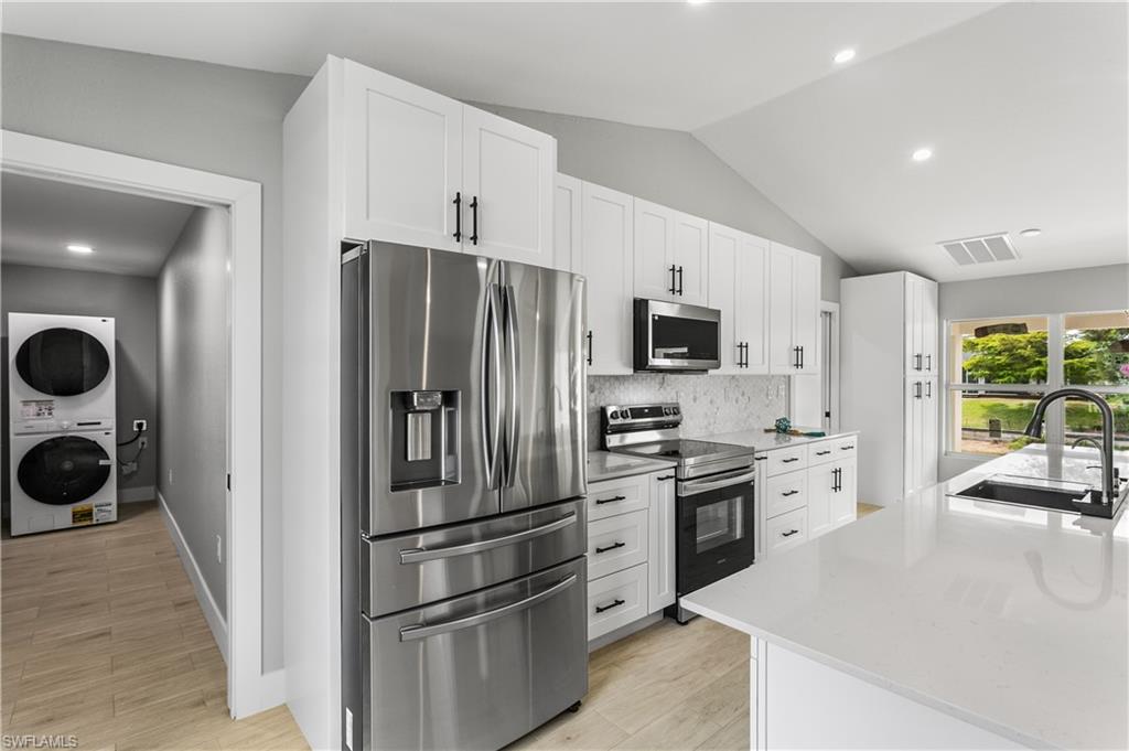 The kitchen is fully equipped with stainless steel appliances, including a French door refrigerator, smooth-top range, built-in microwave, and dishwasher, blending style with everyday functionality.