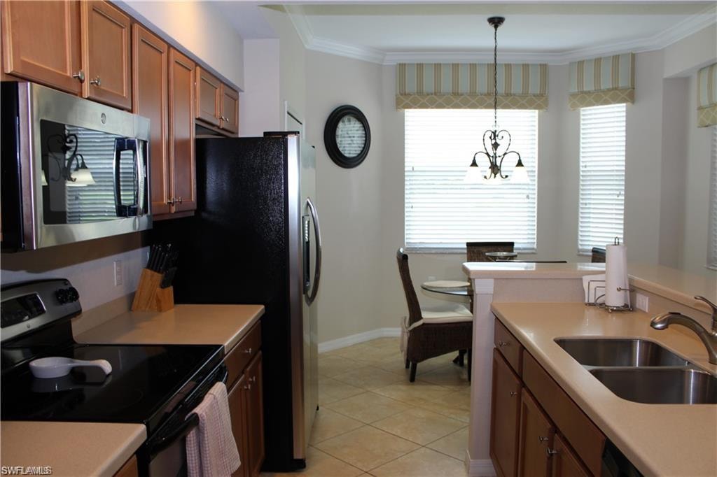 Kitchen with crown molding, an inviting chandelier, a sink, appliances with stainless steel finishes, and brown cabinetry