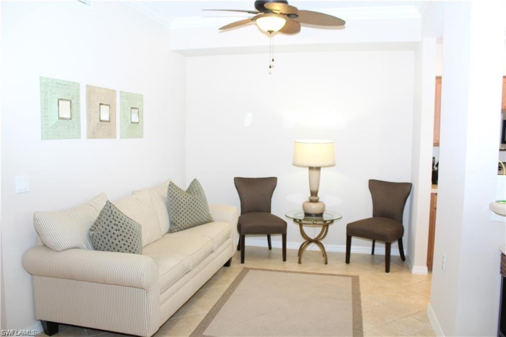 Living room with baseboards, light tile patterned floors, crown molding, and a ceiling fan