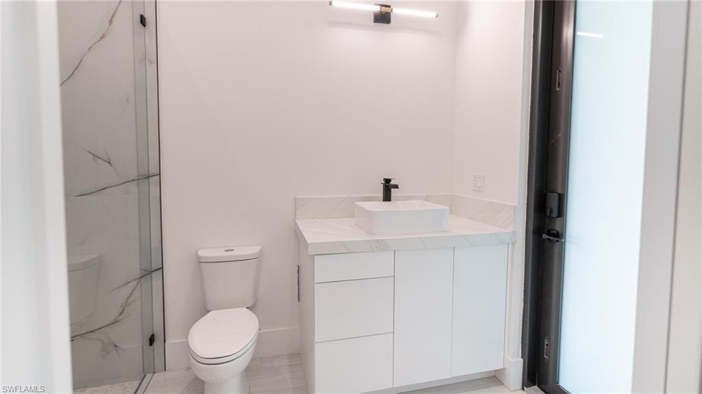 Bathroom featuring a contemporary vanity with a vessel sink, quartz countertop, and black hardware