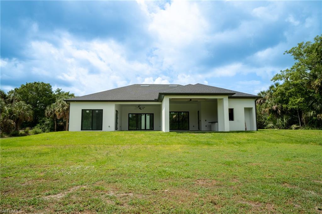 Expansive green lawn surrounds a contemporary residence with a dark shingle roof