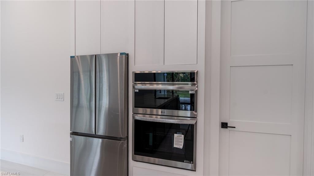 Stainless steel French door refrigerator and built-in double oven appliances integrated into white cabinetry